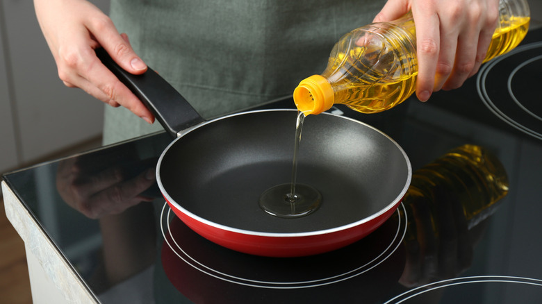 Person pouring oil into pan.