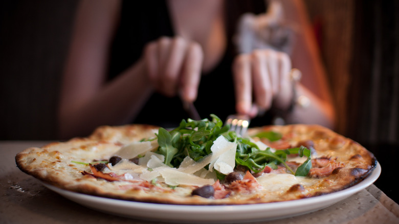 eater slicing into pizza