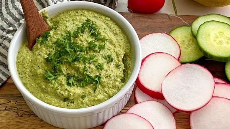 Overview of zucchini hummus in bowl next to radish and zucchini slices