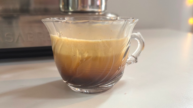 Glass teacup with espresso shot in it on white table