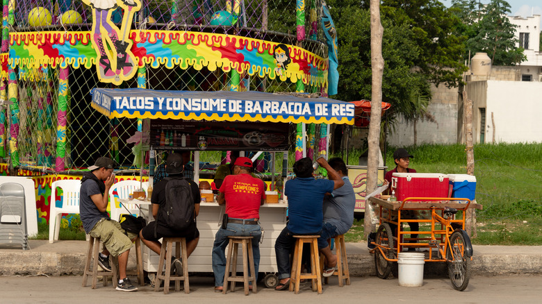 Men sitting at a taco cart