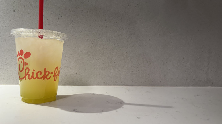 Chick-fil-A key lime lemonade drink cup with straw on white counter.