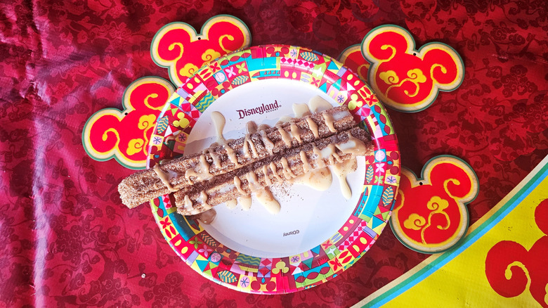 Vietnamese Coffee Churro, drizzled with icing, on a festive Lunar New Year plate.