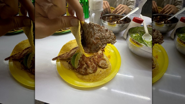 A meat taco folded with no salsa over table full of food