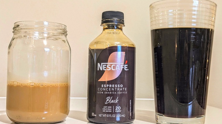 Small coffee with milk in glass and large black coffee in glass with black concentrate bottle.