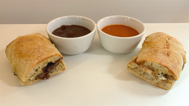 two panera ciabatta dippers next to white bowls of soup on white table