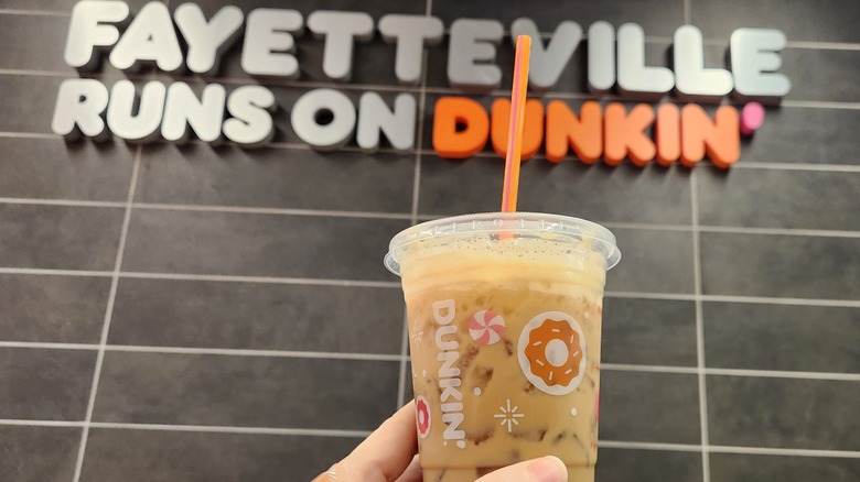 hand holding Sabrina's Brown Sugar Shakin' Espresso in front of Fayetteville Runs on Dunkin' sign