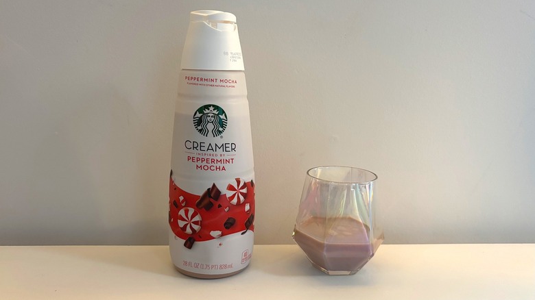 Bottle of Starbucks peppermint mocha creamer next to glass of creamer on white background