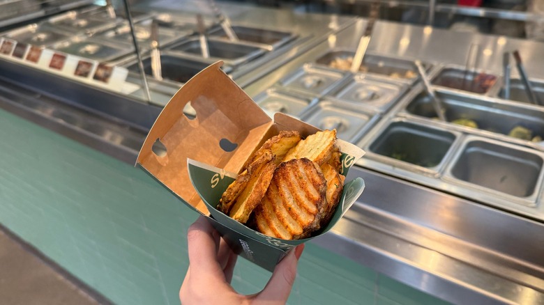 sweetgreen french fries being held in front of salad station at restaurant