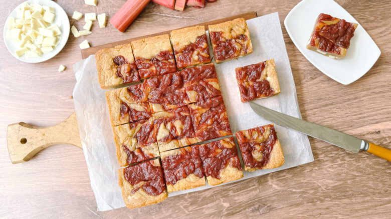Rhubarb and white chocolate blondies on cutting board with knife