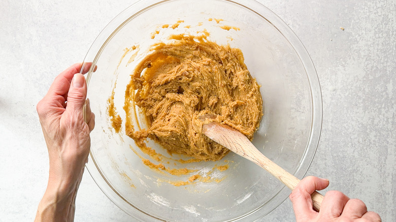 Stirring blondie batter with wooden spoon in glass bowl