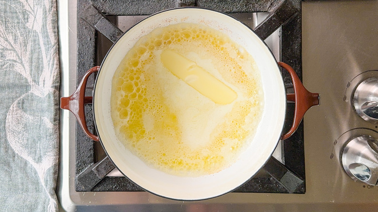 Butter melting in saucepan on stovetop.