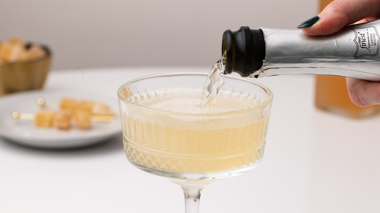 Pouring prosecco into a cocktail