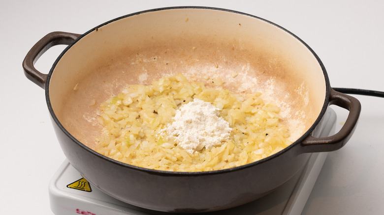 adding flour to sauteed onions