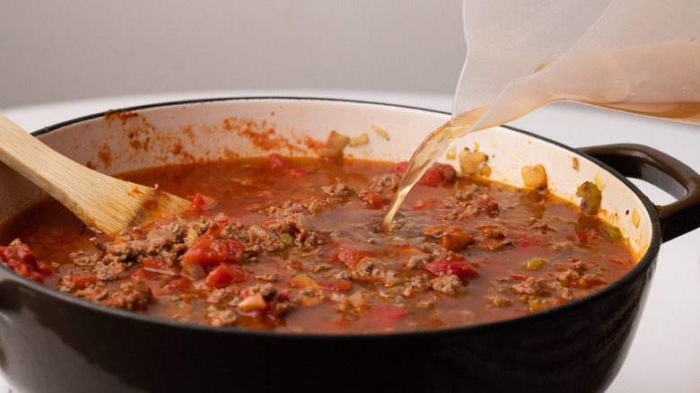 Pouring stock into chili 