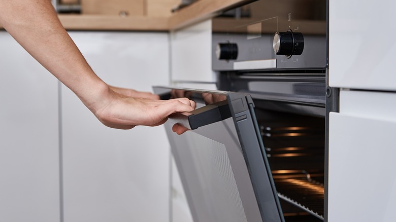 Woman's hand opening oven's door