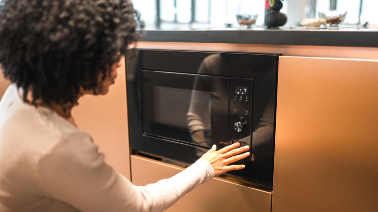 woman pressing microwave button