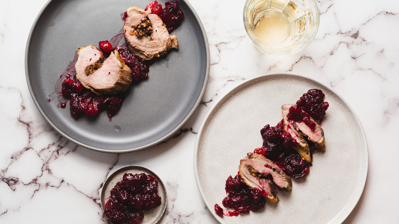 Two sliced stuffed duck breast plates with wine and sauce