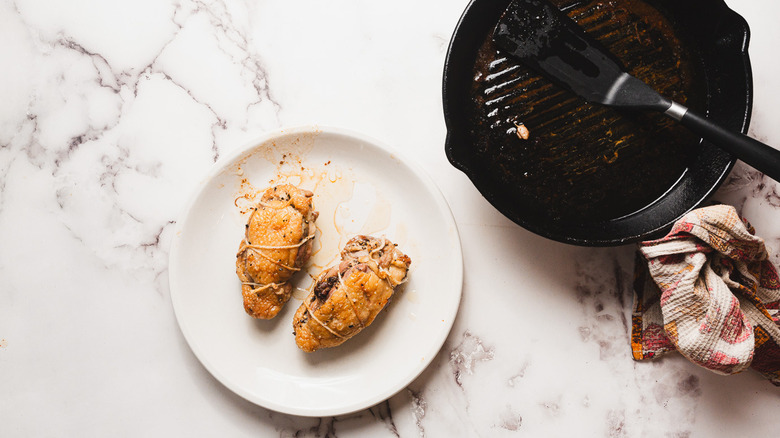 Two cooked duck breasts near pan