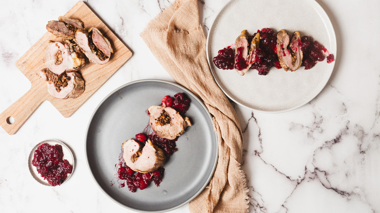 Two sliced stuffed duck breast plates with napkin and sauce