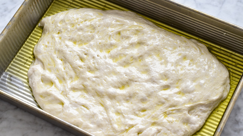 adding bread dough to baking pan