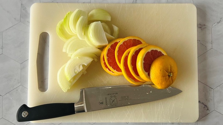 sliced orange and onion with knife on cutting board