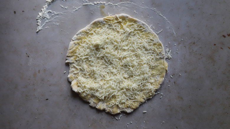 Scattered mozzarella cheese on dough