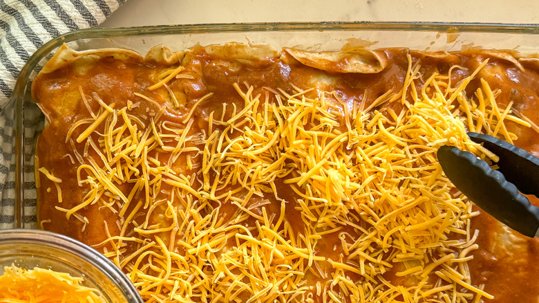 tongs adding cheese to dish