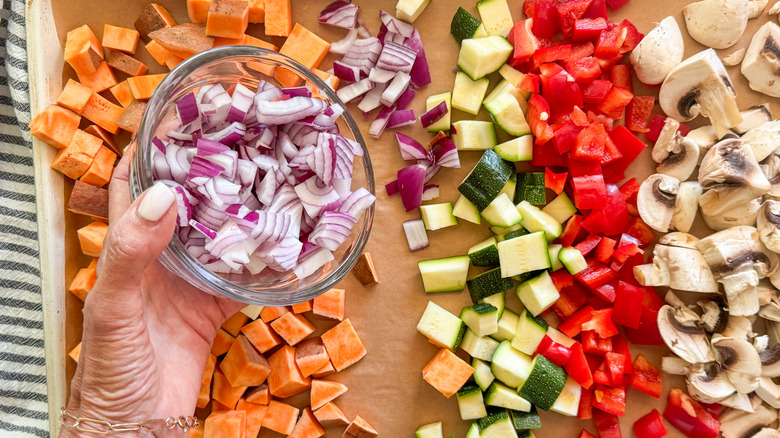 hand adding onions to pan