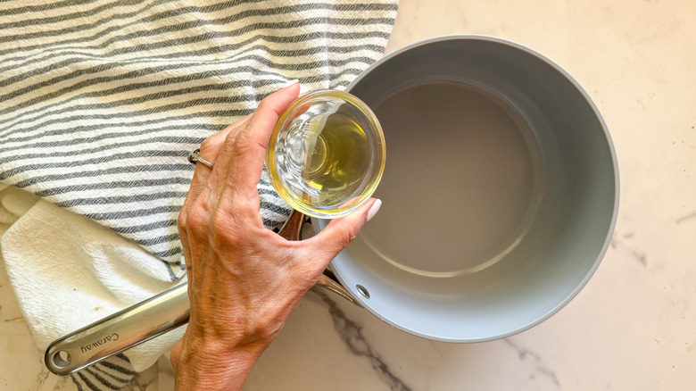 hand adding oil to pot