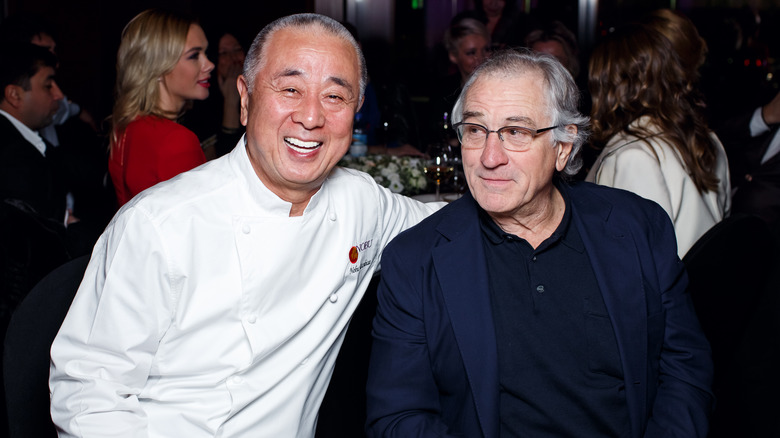 Robert De Niro in black and glasses with Nobuyuki "Nobu" Matsuhisa in white chef uniform