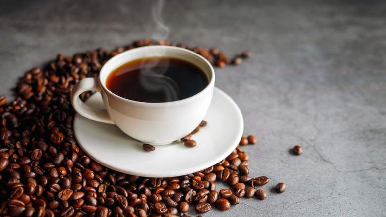 Cup of coffee surrounded by coffee beans