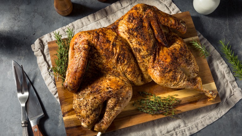 Spatchcocked chicken with herbs on wooden board