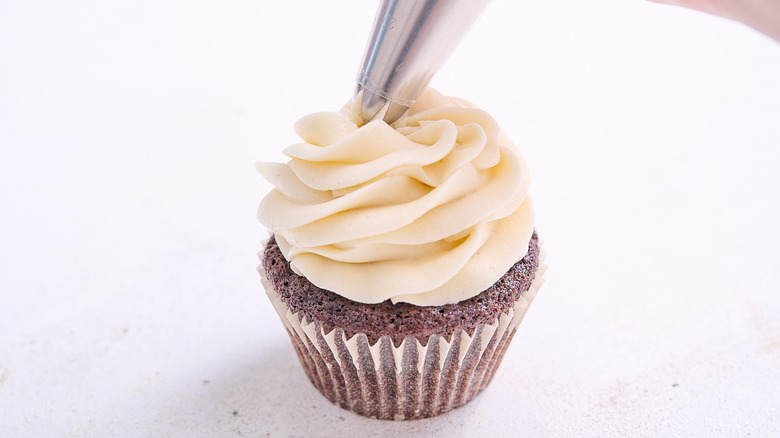 piping frosting onto cupcakes