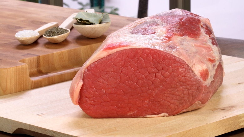 A raw rump roast on a wooden board