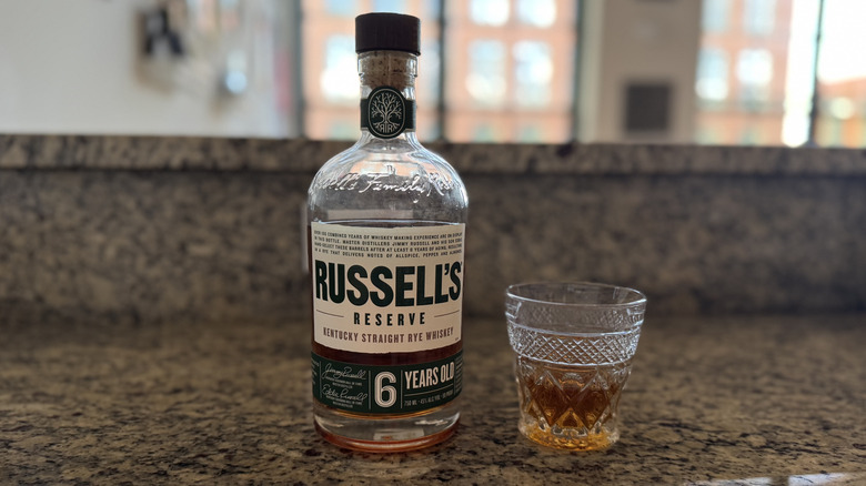 Neat glass of Russell's Reserve rye next to bottle on counter