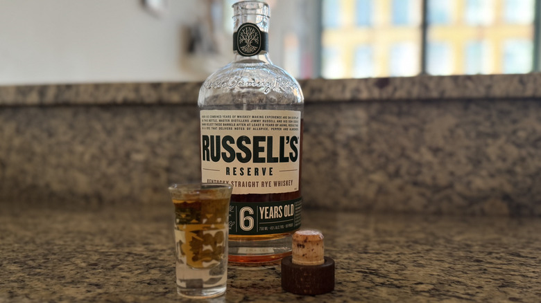 Shot poured beside opened Russell's Reserve rye bottle