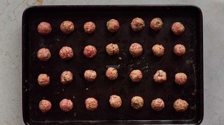 uncooked meatballs on sheet pan
