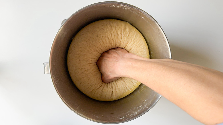 Punching down risen flatbread dough in mixer bowl