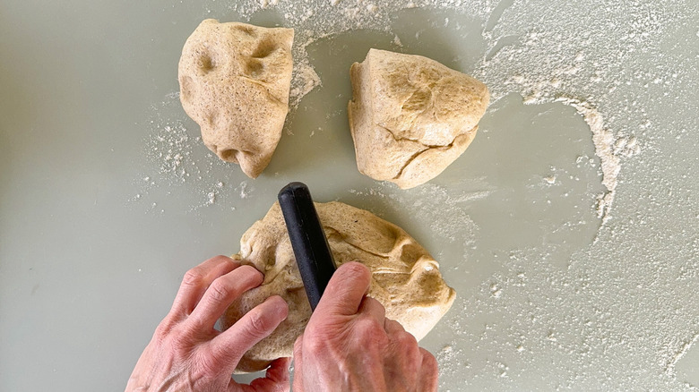 Flatbread dough sections on floured work surface with dough cutter