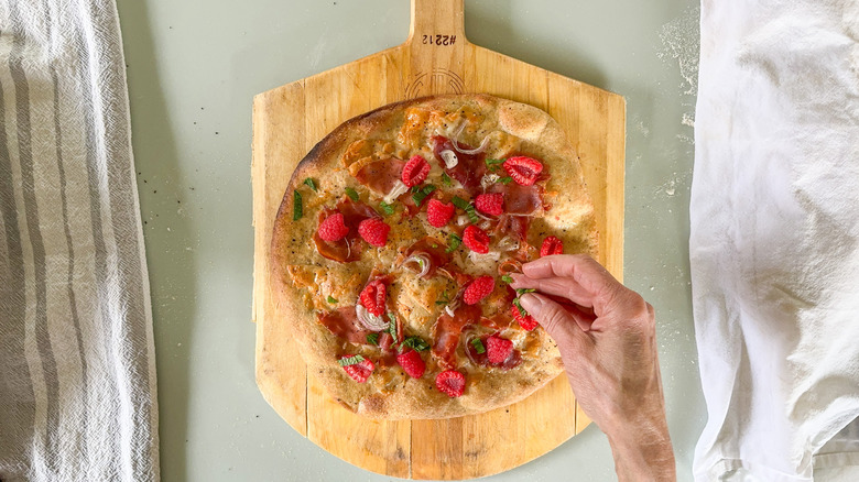 Adding mint and raspberries to rye flatbread with prosciutto