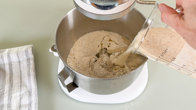 Pouring foamy yeast into flour in stand mixer bowl