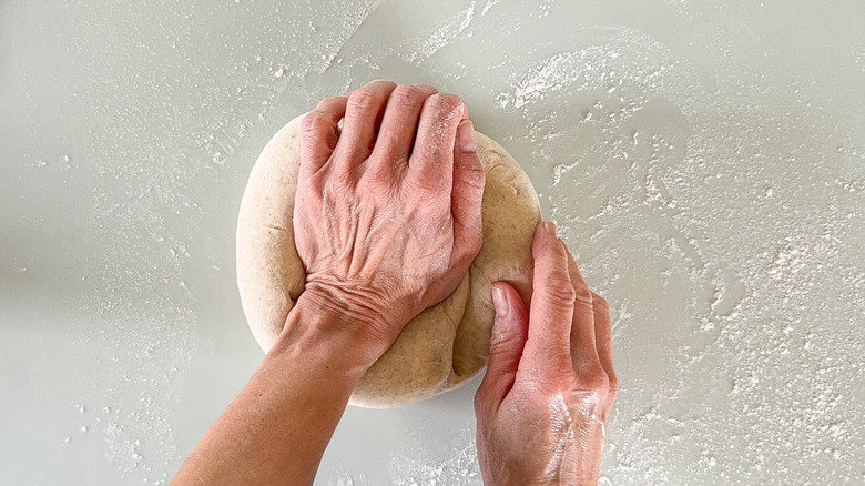 Kneading flatbread dough on floured countertop