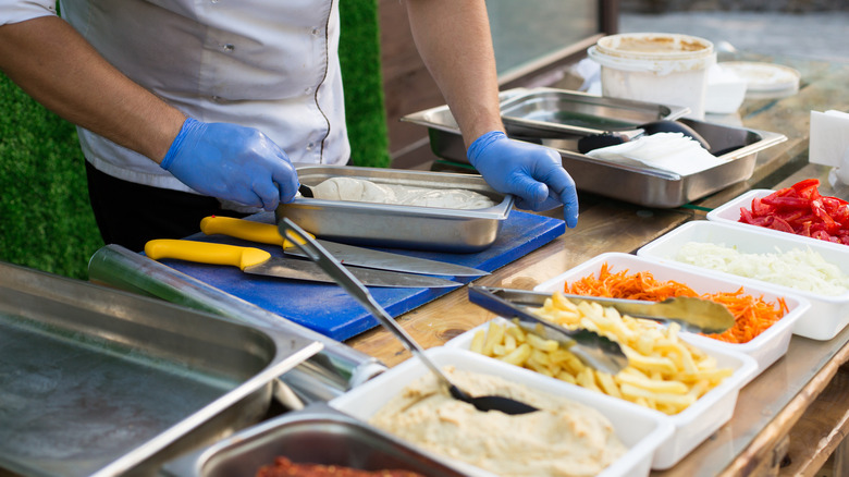 street vendor with compartments of fillings for pita