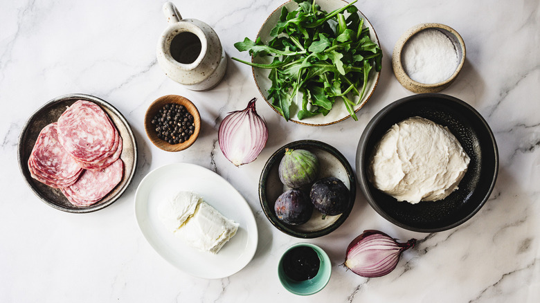 ingredients for fig and salami flatbread on marble counter