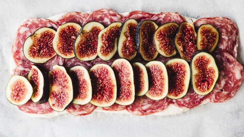 flatbread with salami and figs on baking sheet