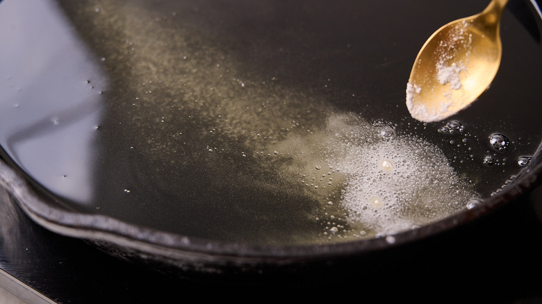 testing oil with flour in skillet