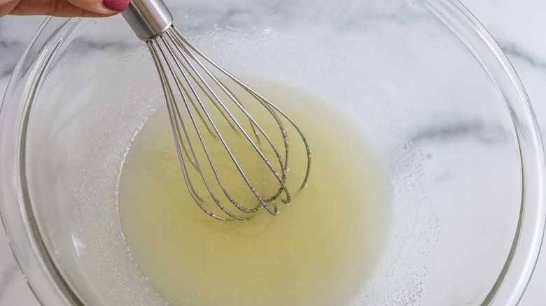 hand stirring liquid in bowl