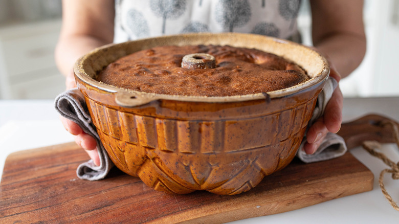 Someone holding a bundt cake pan with mitts