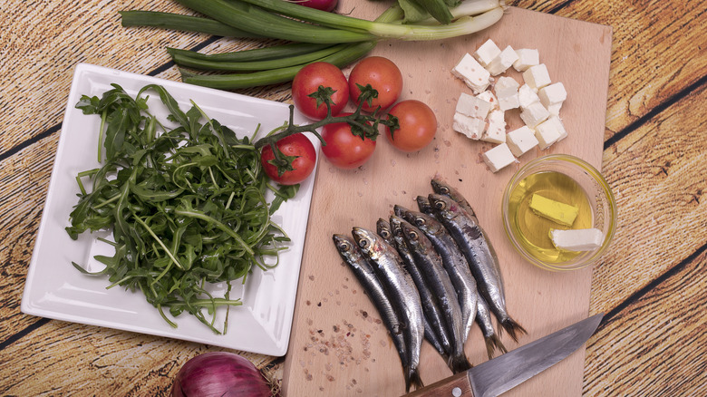 Sardines, feta, arugula and tomatoes on table